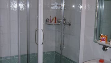 A bathroom with a glass-enclosed shower, a toilet, and a sink.