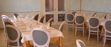 Un comedor con varias mesas y sillas, una puerta con paneles de vidrio esmerilado y apliques de pared.