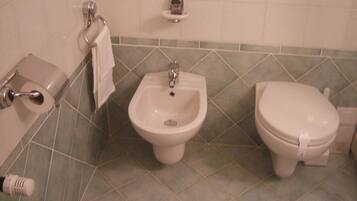 Un baño con bidé, inodoro y lavamanos.