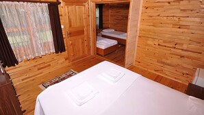 Una habitación de cabaña de madera con una cama, una mesita y una ventana con cortinas.