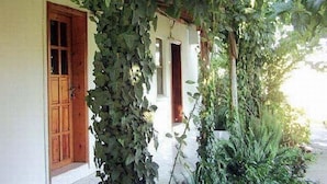 Un edificio con porche cubierto, puertas de madera y una pared cubierta de plantas trepadoras.