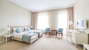 A hotel room with two beds, a desk, a chair, and a television.