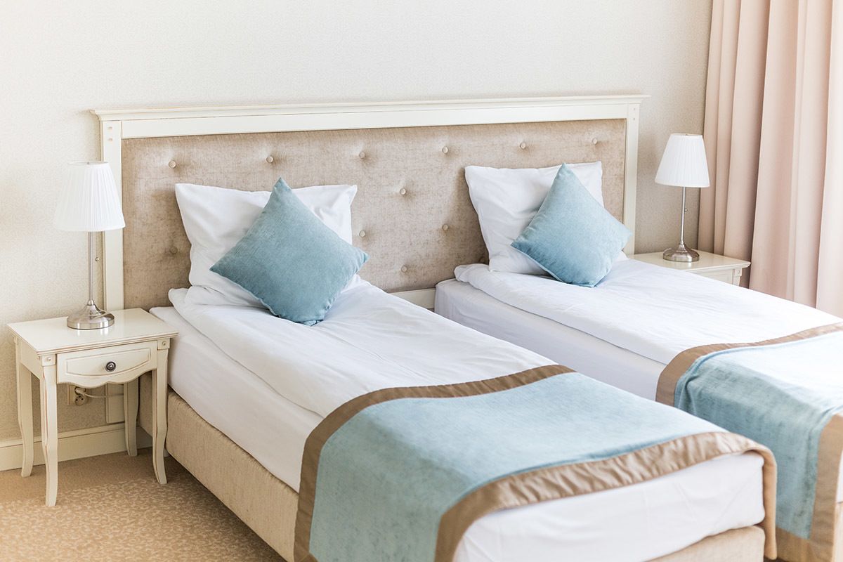 A double bed with a tufted headboard, two bedside tables, and a lamp on each side.