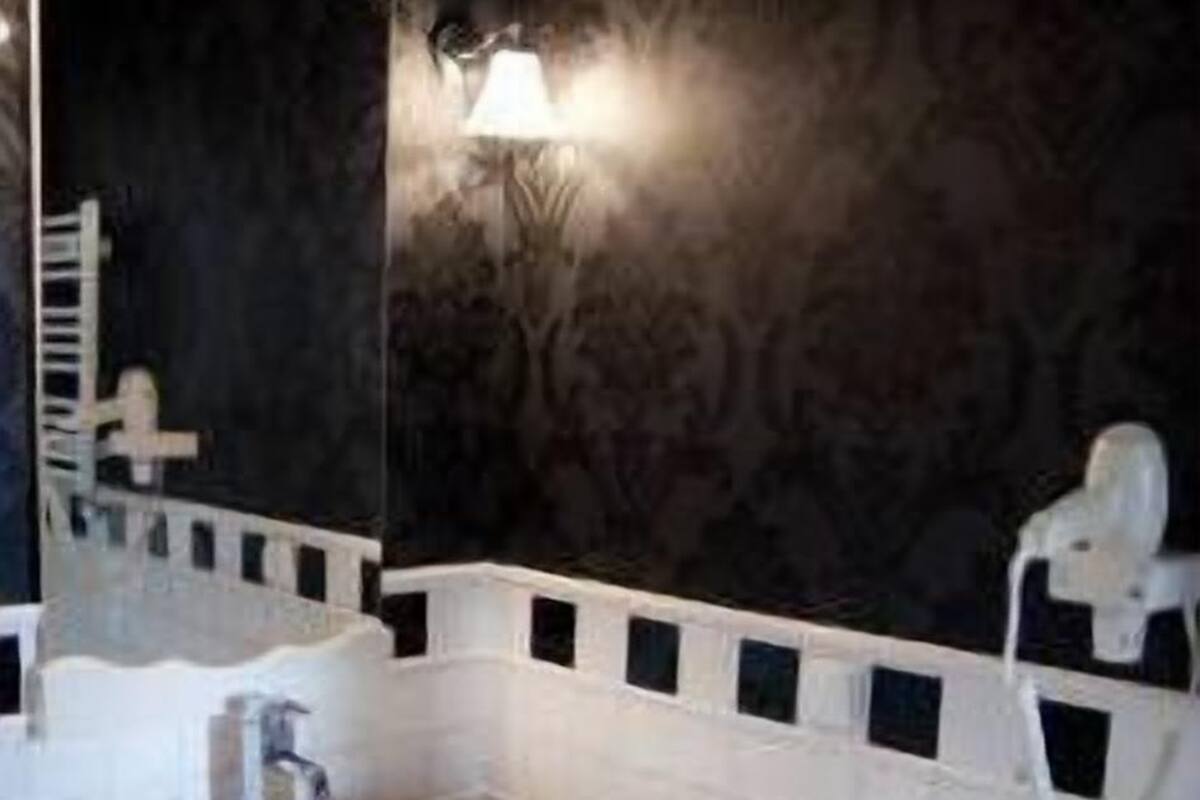 A modern bathroom with a white sink, dark wall, and a mirror.