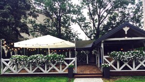 A covered outdoor area with string lights, white lattice railings, and potted plants.