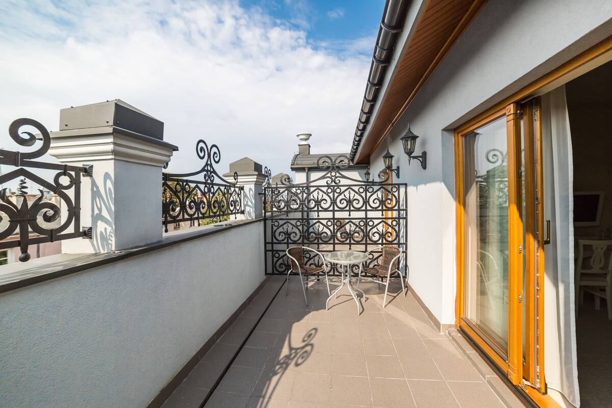 A balcony with a metal fence, a table with chairs, and a sliding glass door.