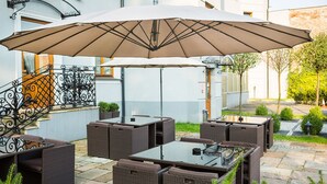 An outdoor patio with wicker furniture and a large umbrella.