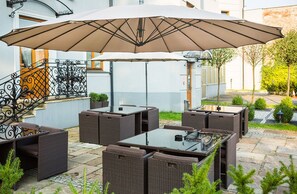 An outdoor patio with wicker furniture and a large umbrella.