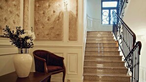Un magnifique escalier avec un sol en pierre polie et une rampe en fer forgé.