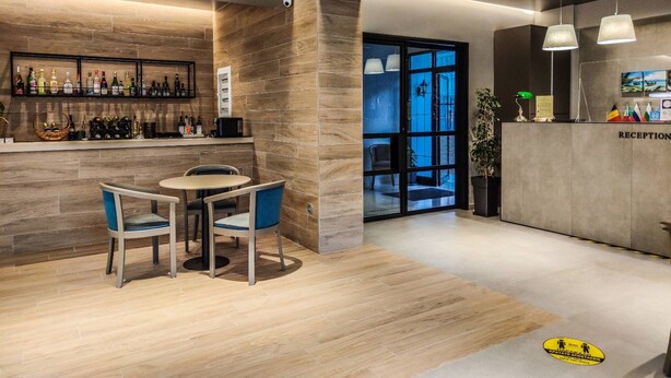 Un área de recepción moderna con barra, asientos y vista a través de un ventanal.