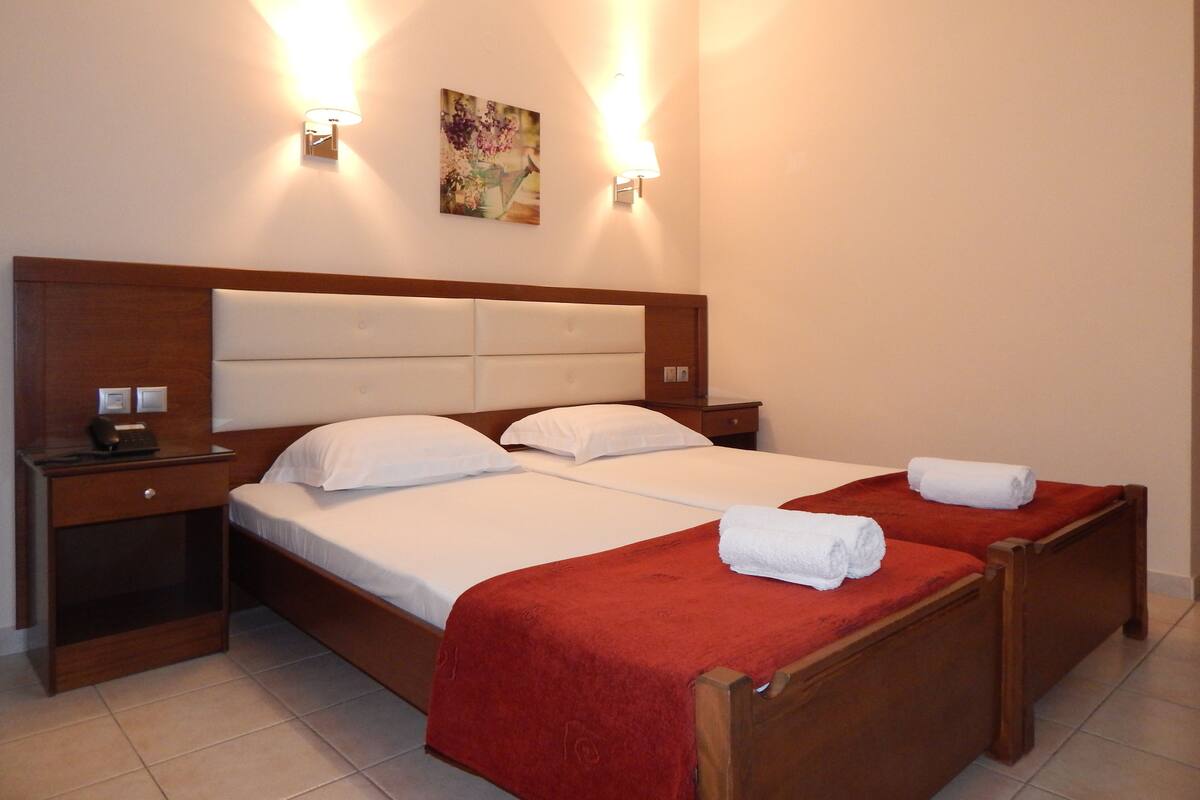 Una habitación de hotel con una cama grande, dos mesitas de noche y un cuadro en la pared.