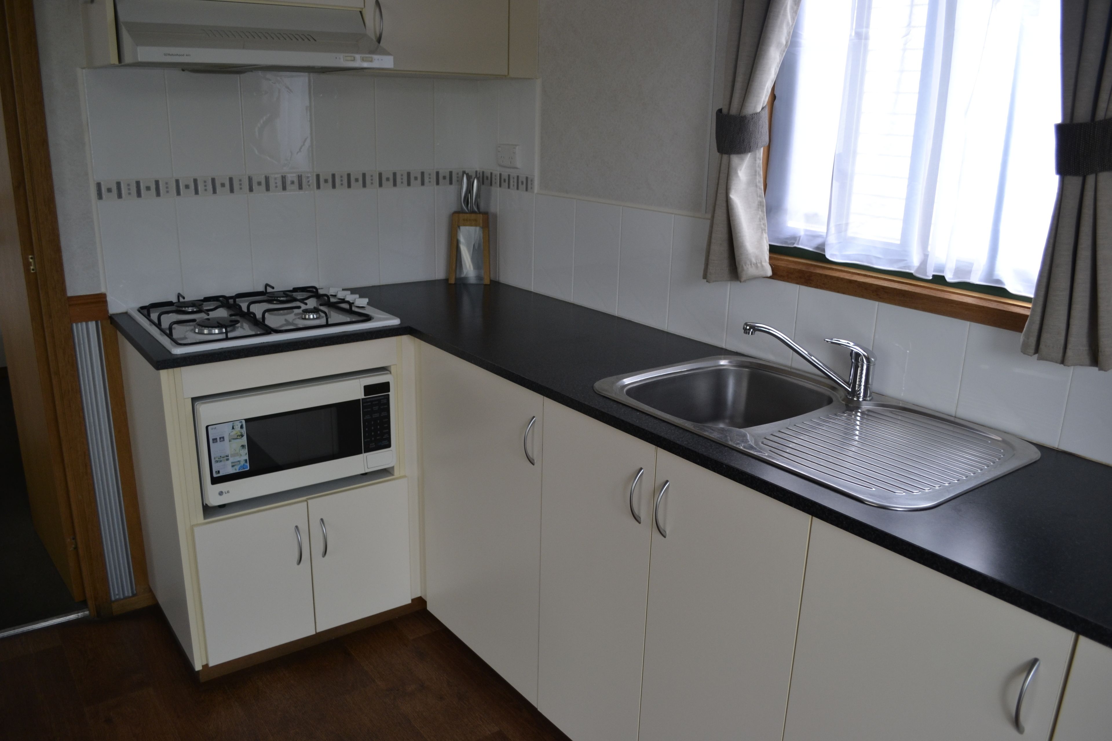 A compact kitchen with a gas stove, microwave, and sink.