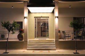 Entrada de hotel con puerta de vidrio, escalones y un letrero.