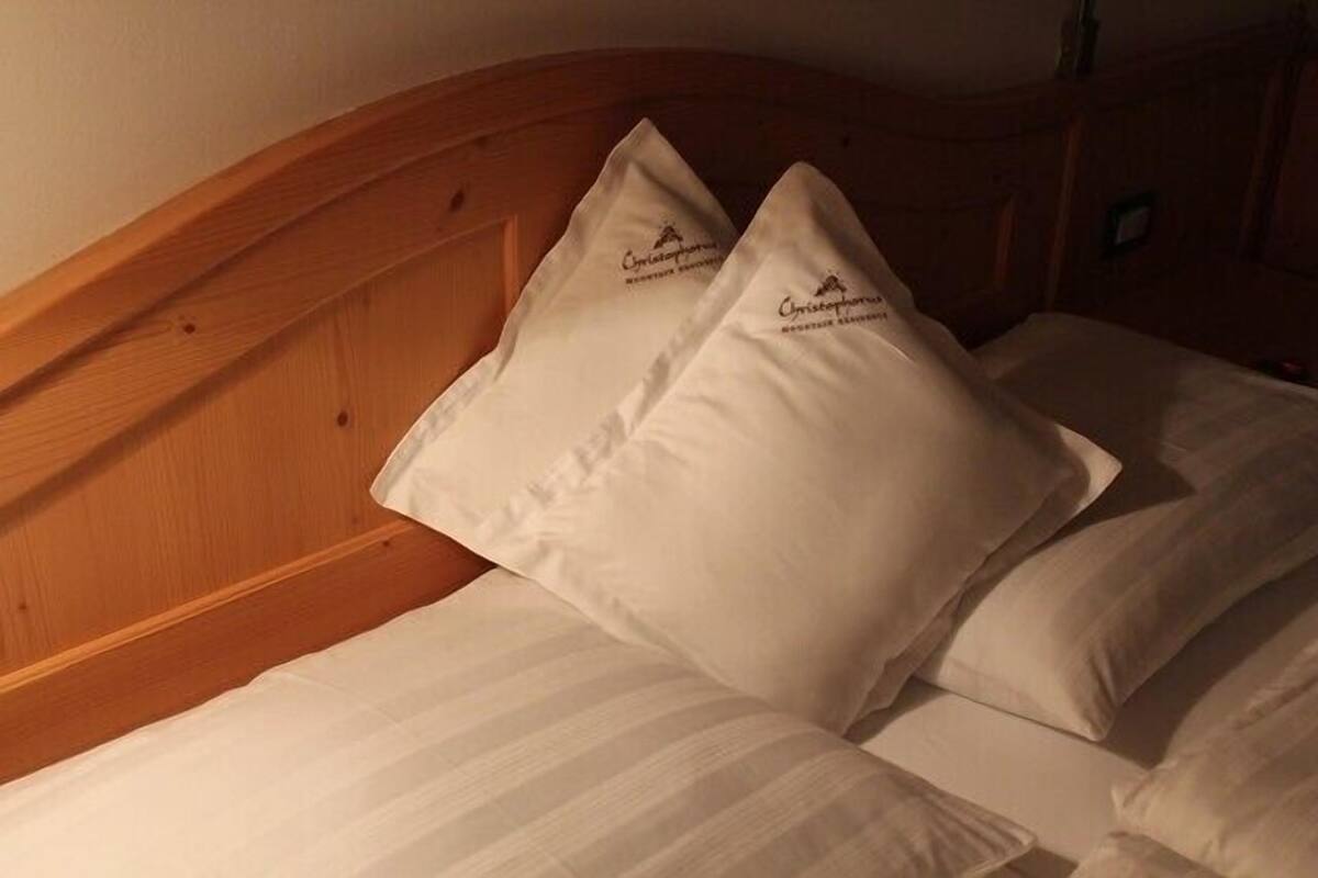 A bed with two pillows and a wooden headboard.