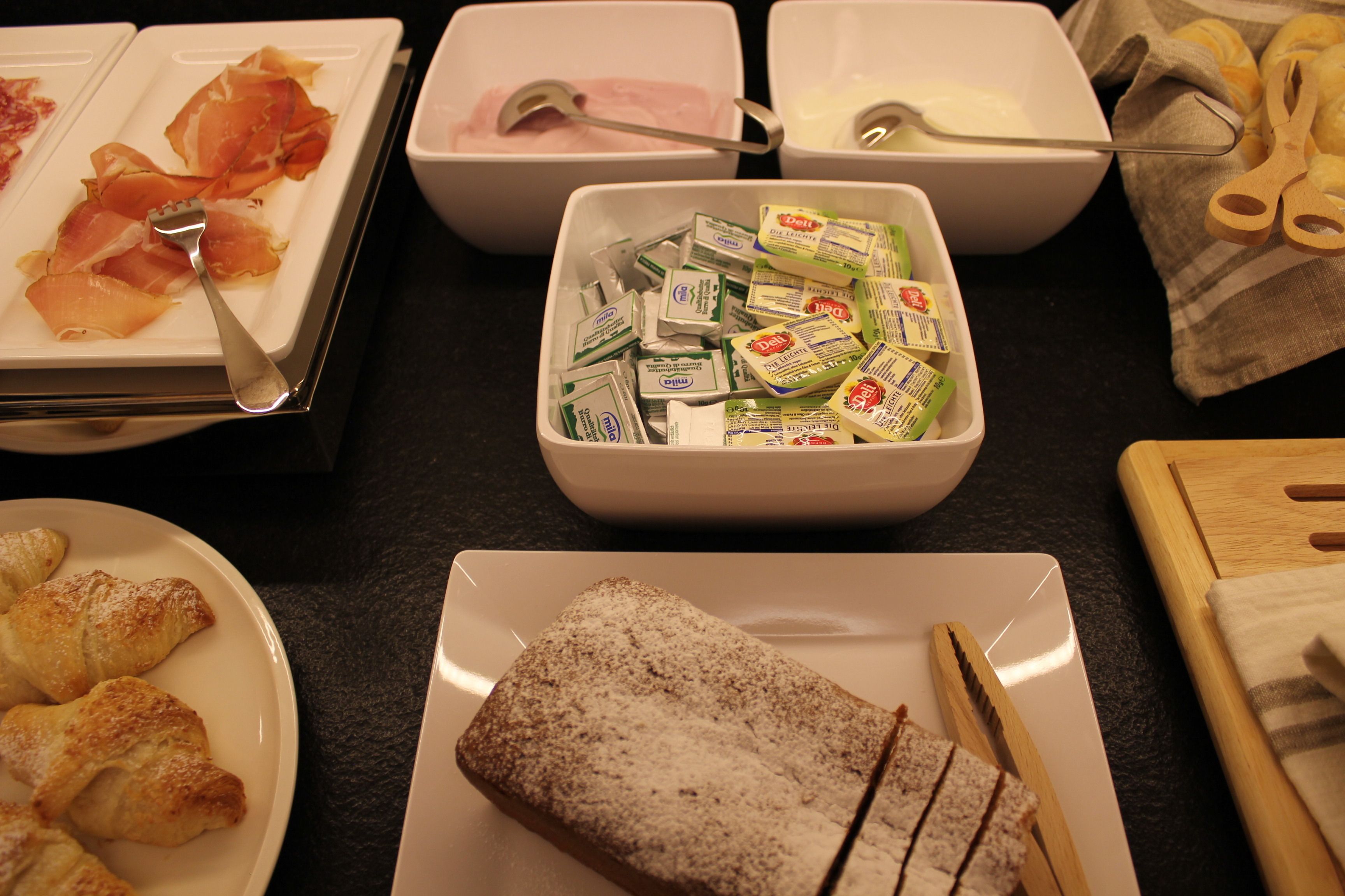 Una mesa de buffet con diversos alimentos, incluyendo pasteles, queso y productos lácteos.