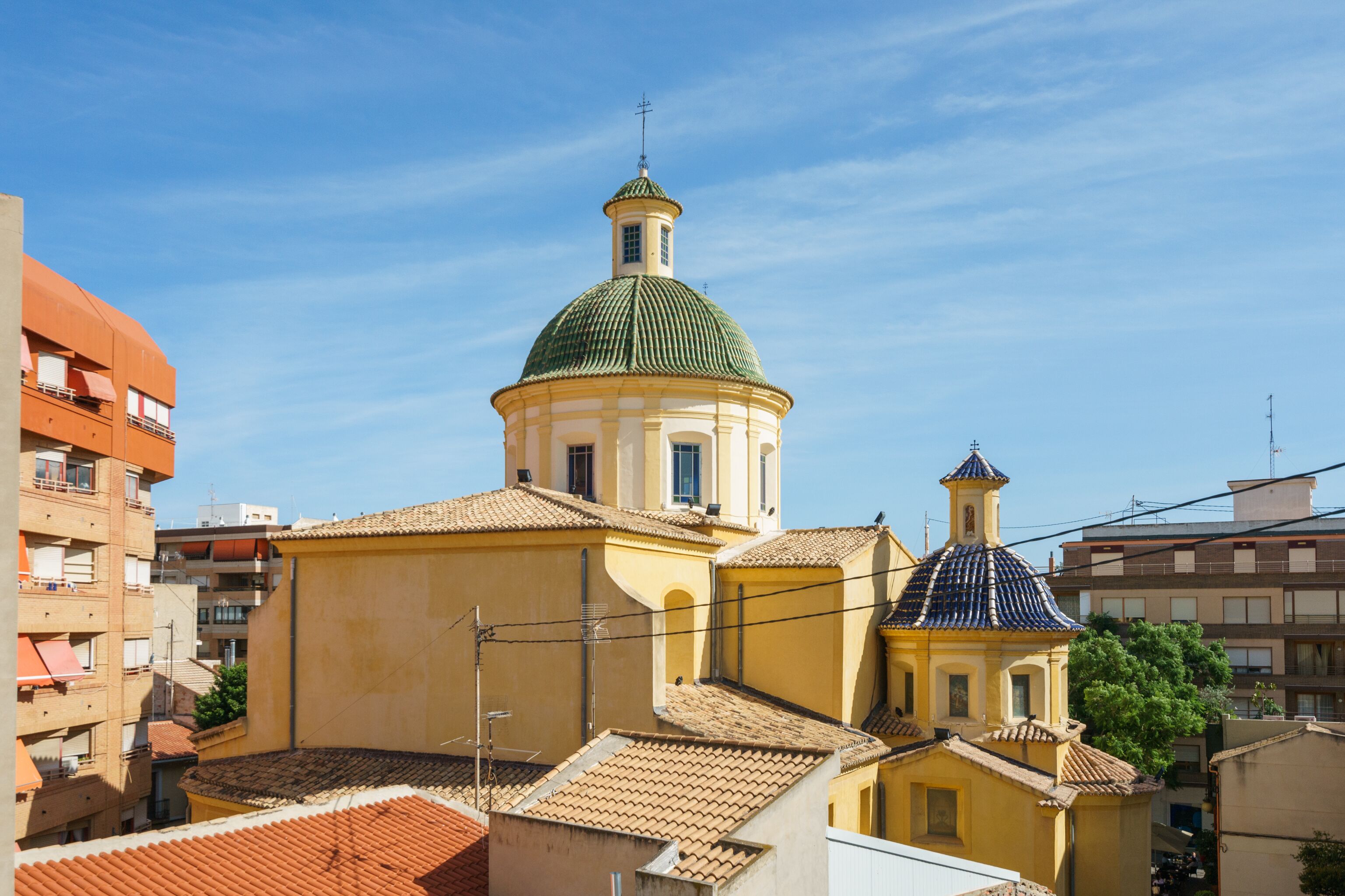A historic building with a prominent dome and a smaller adjacent structure, surrounded by other buildings.