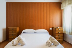 A hotel room with a wooden paneled headboard, a bed with white linens, two wooden nightstands, and a window with curtains. - Hostal Casa Antonio by Vivere Stays (San Vicente del Raspeig)