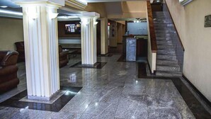 A lobby with marble flooring, columns, a staircase, and a reception desk. - Sakr Hotel (Penapolis)