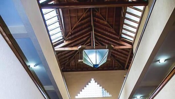 A spacious interior with a high ceiling, skylights, and a central staircase. - Sakr Hotel (Penapolis)