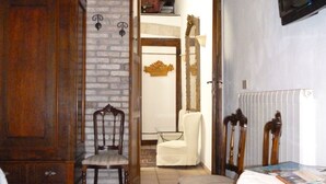Una stanza con un'armadio in legno, una poltrona bianca, un tappeto decorato e un televisore fissato alla parete.