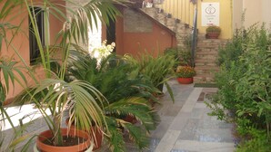 Un cortile con piante in vaso, una scala in pietra e un muro giallo.