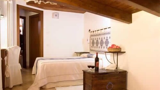 Una camera da letto con un letto, un comò in legno, un tavolo con una candela e una sedia.
