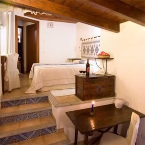 A bedroom with a bed, a wooden chest of drawers, a table with a candle, and a chair. - Il Giardino Segreto (Cagliari)