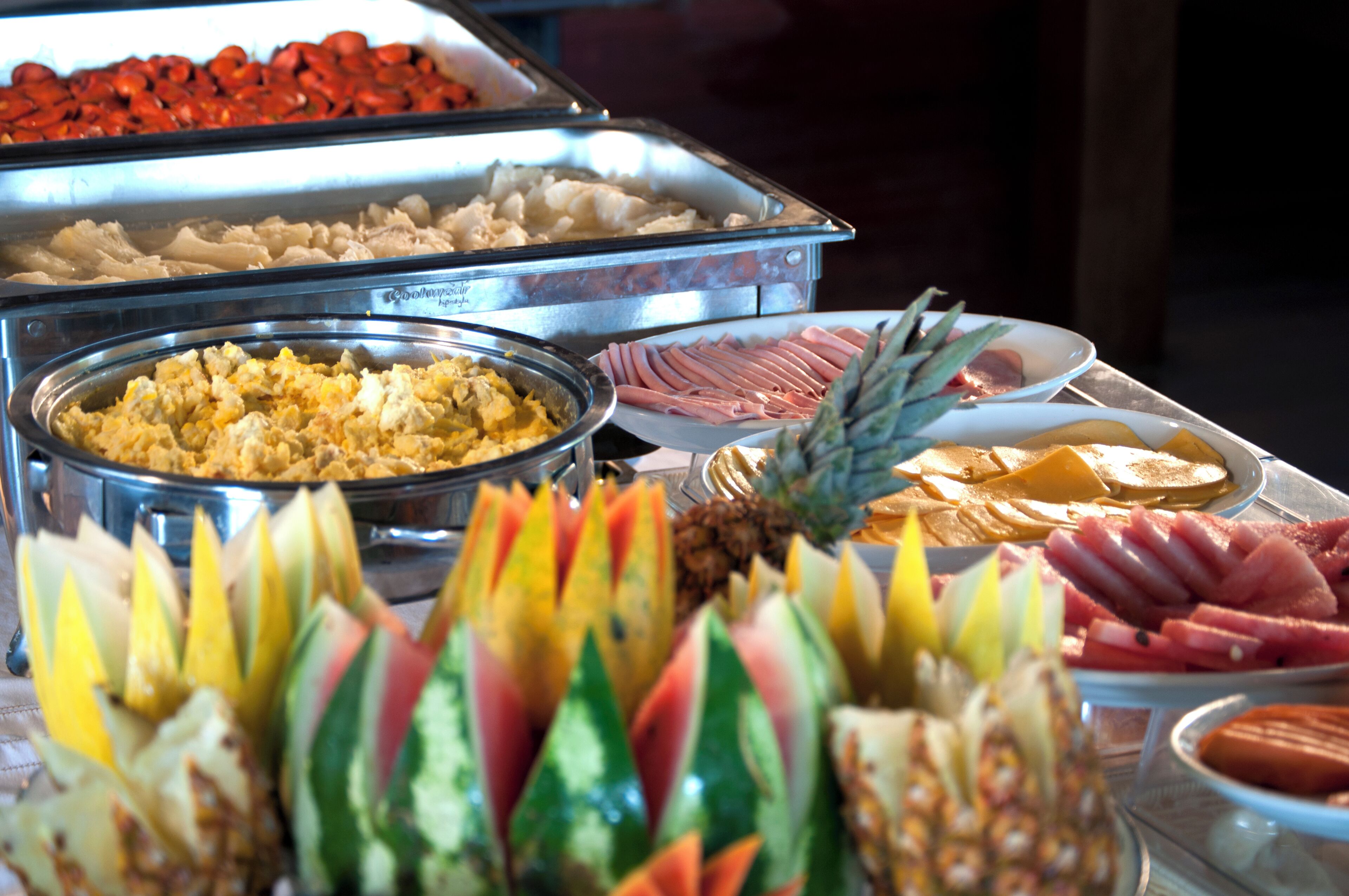 A buffet with various food items including fruits, meats, and other dishes.