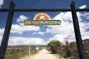Señal de Monte Castelo con un emblema de estrella, un camino de tierra y cielo despejado.