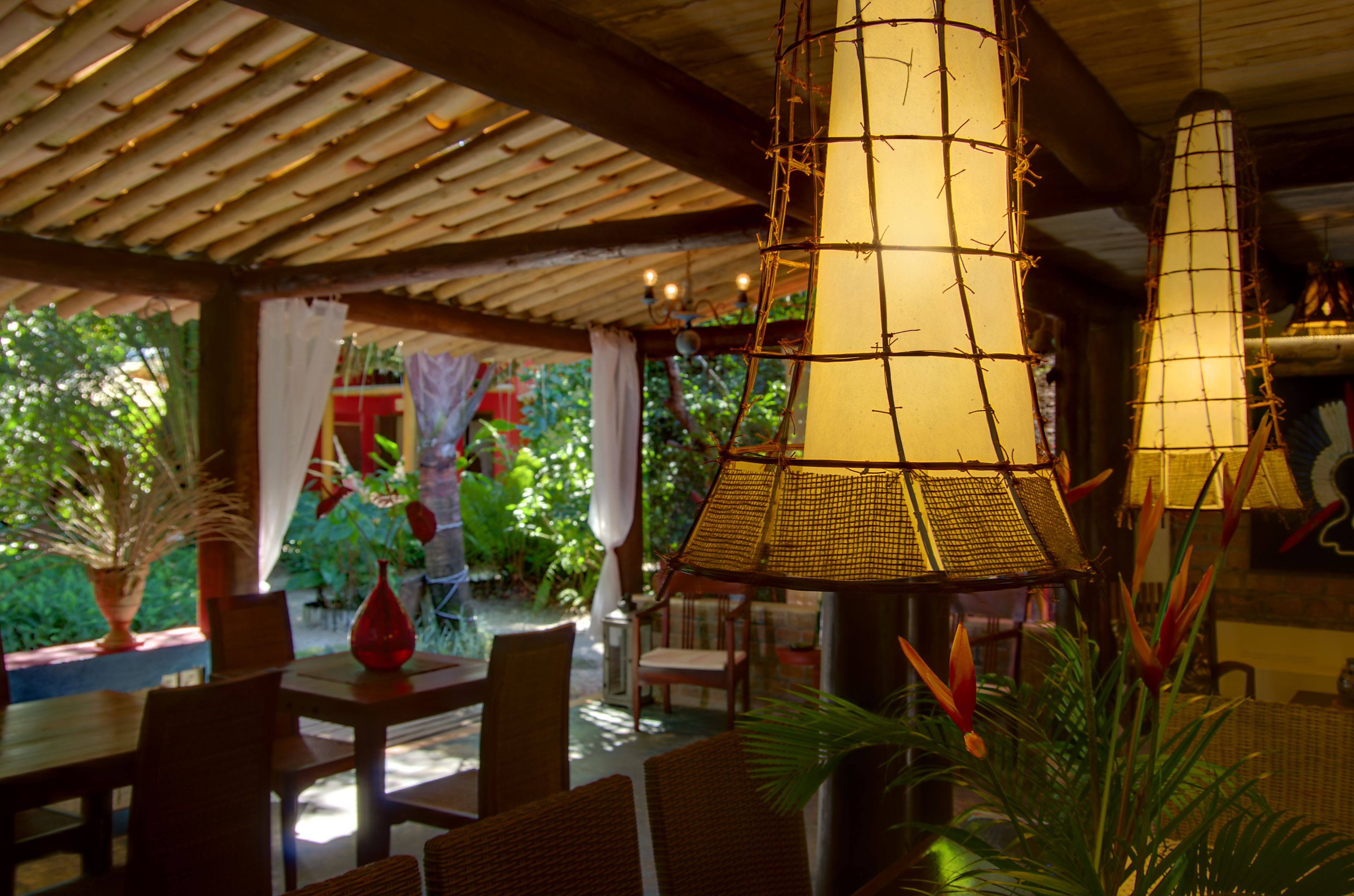 An outdoor dining area with bamboo lamps, wicker furniture, and potted plants.