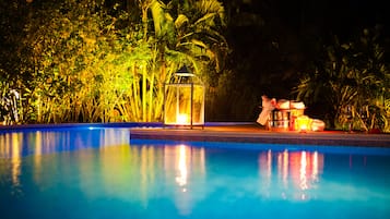 Una piscina al aire libre, sombrillas, sillones reclinables de piscina