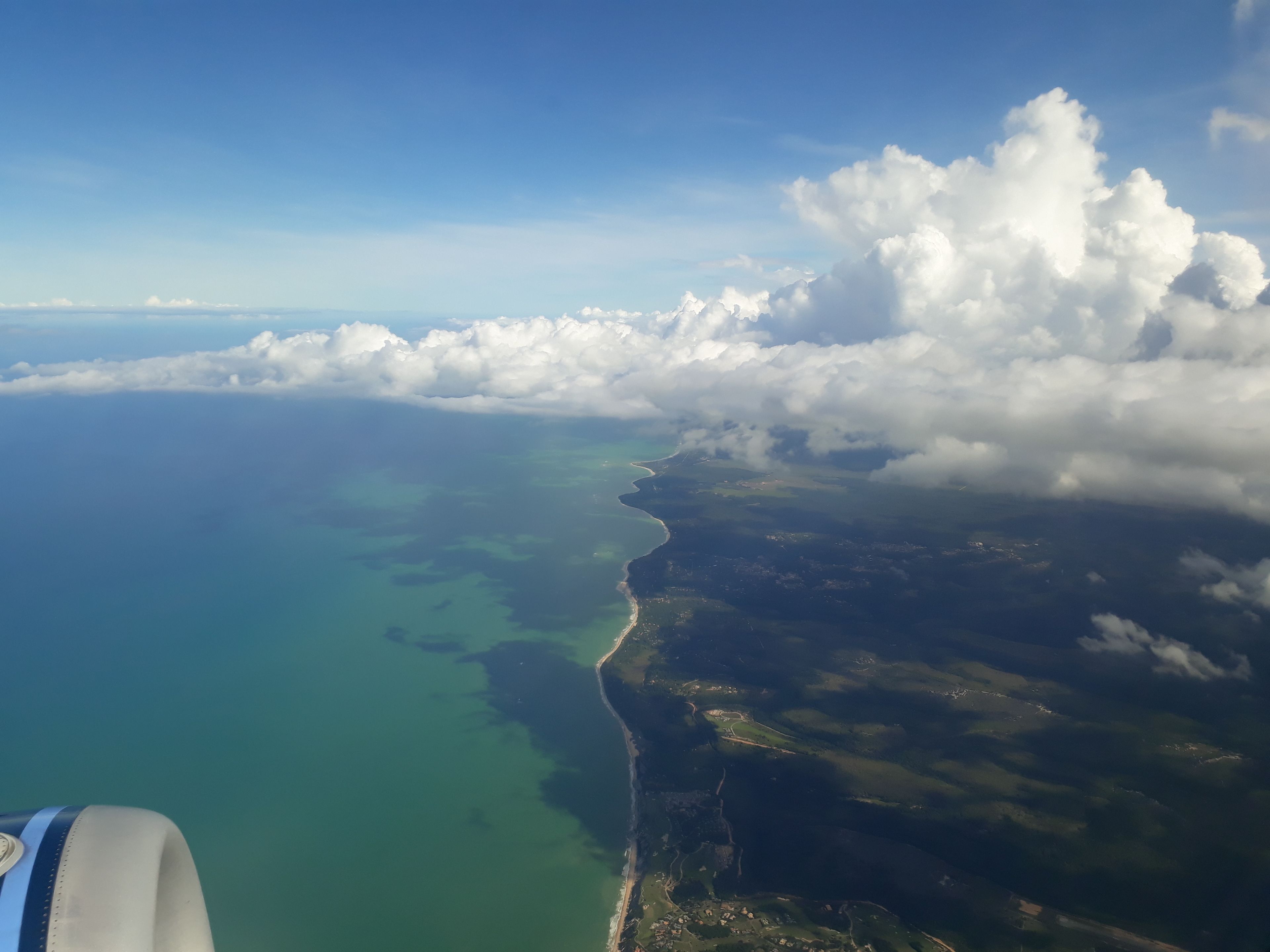 Vista aérea de una costa con cielo despejado y nubes.
