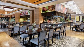 A spacious restaurant with multiple dining tables and chairs, a kitchen area, and a bar. - Intercontinental Tangshan by IHG (Tangshan)