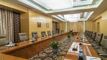A conference room with a long table, chairs, microphones, and water bottles.