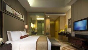A hotel room with a bed, bedside table, TV, and a bathroom visible through a glass door. - Intercontinental Tangshan by IHG (Tangshan)