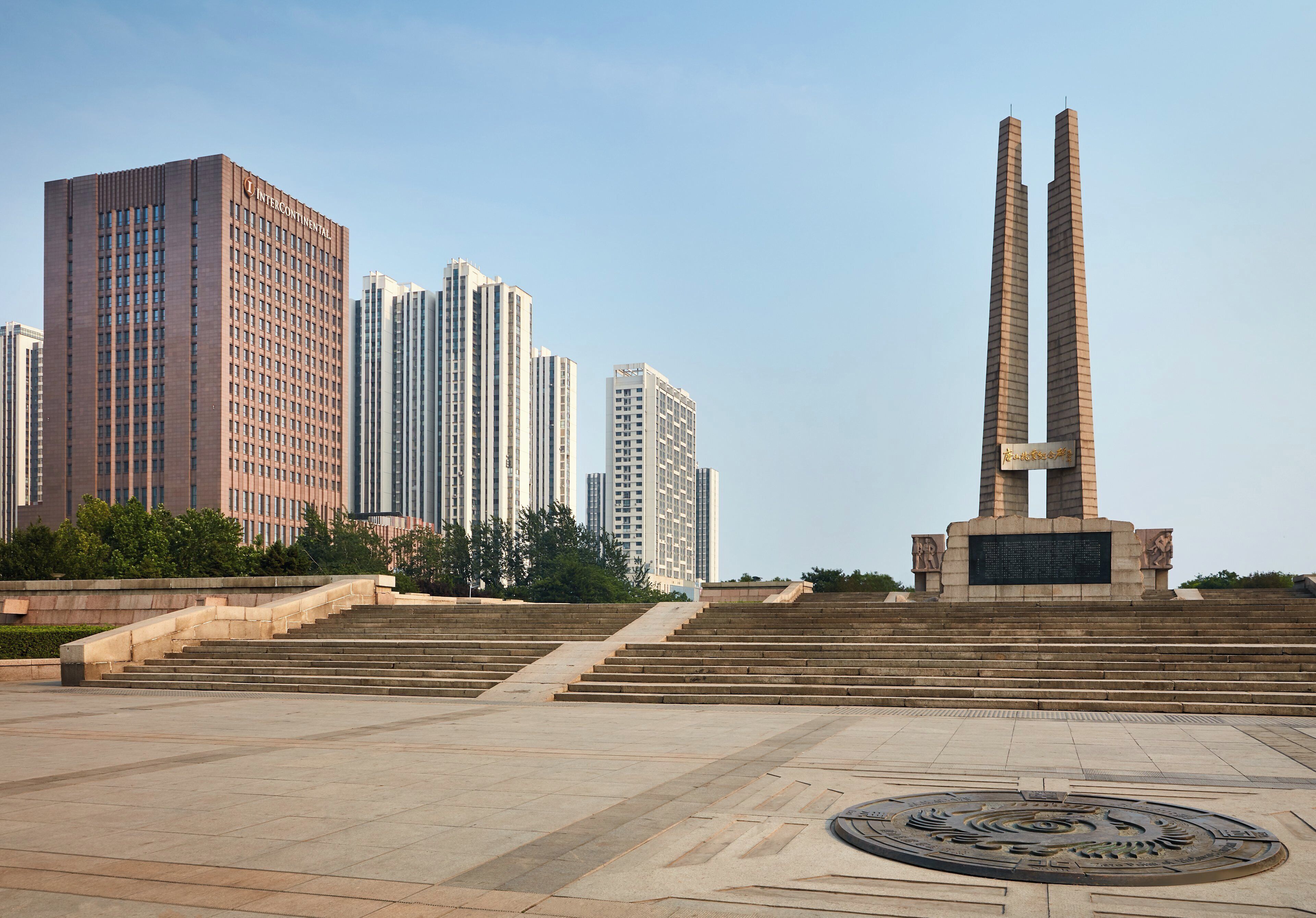 Un monument composé de deux piliers hauts et d’une base circulaire ornée d’inscriptions, le tout étant entouré d’une zone pavée avec des marches menant à sa base.