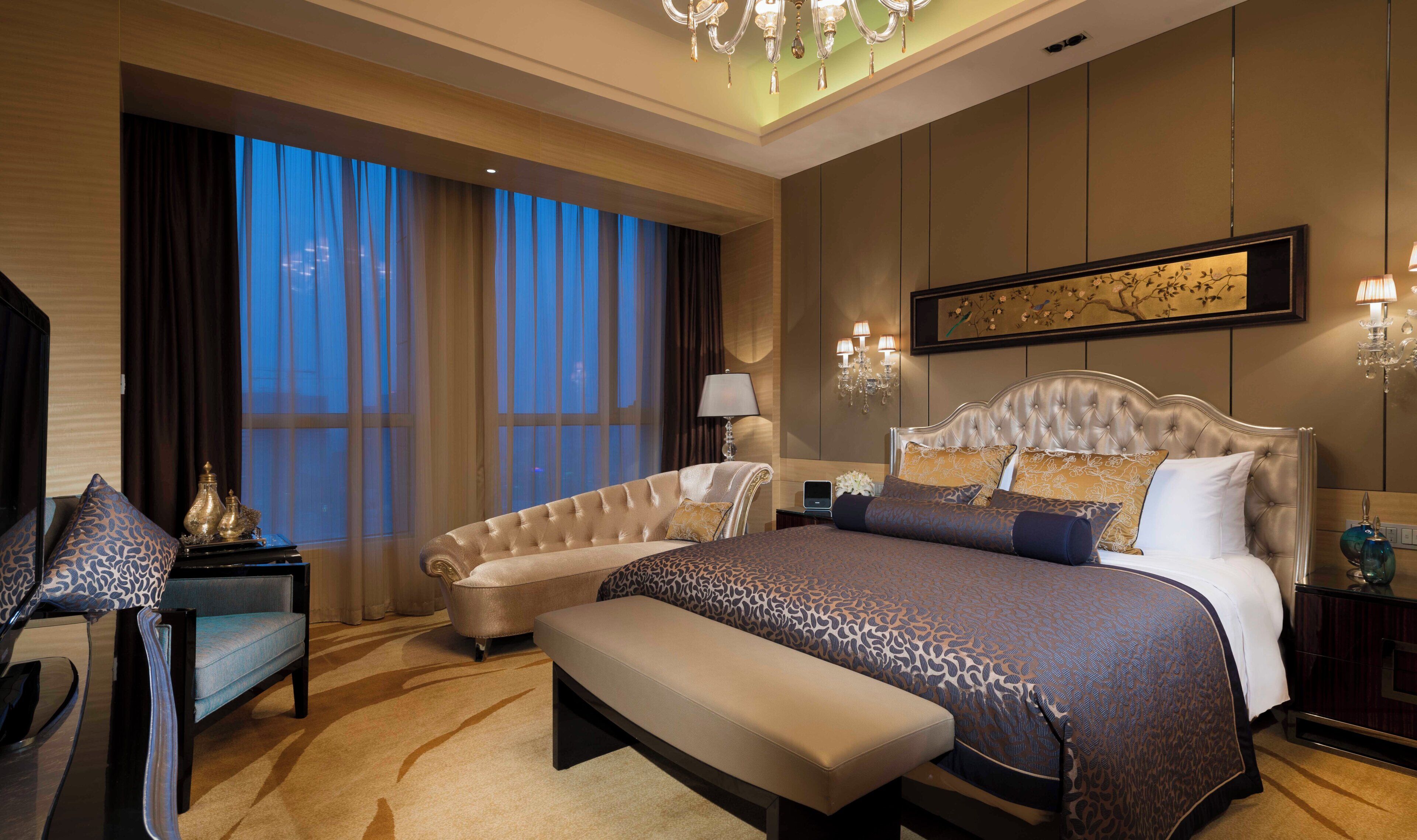 Quarto espaçoso com cama grande, chaise longue e área de estar.