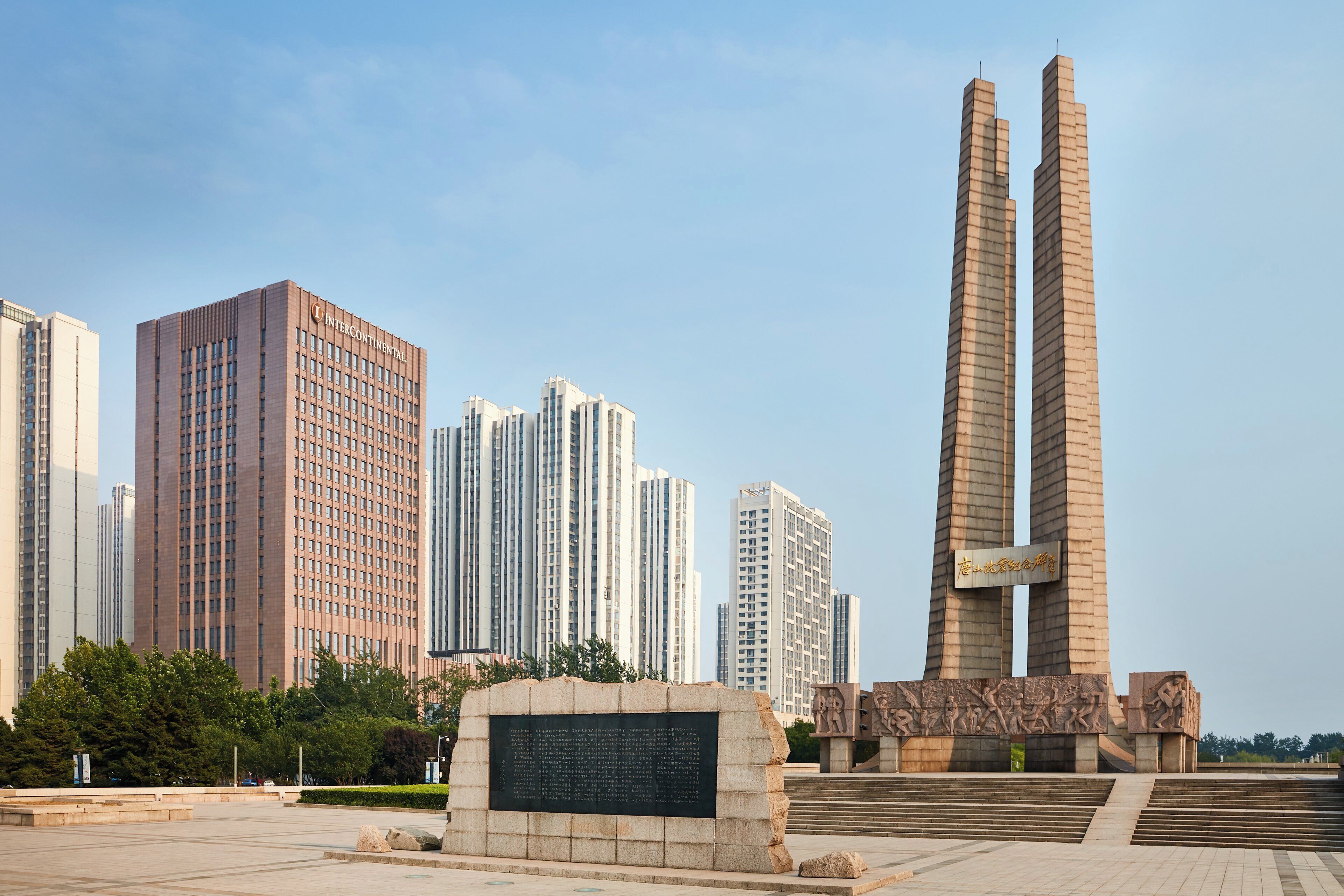 A modern building with a prominent vertical structure and a plaque with inscriptions.