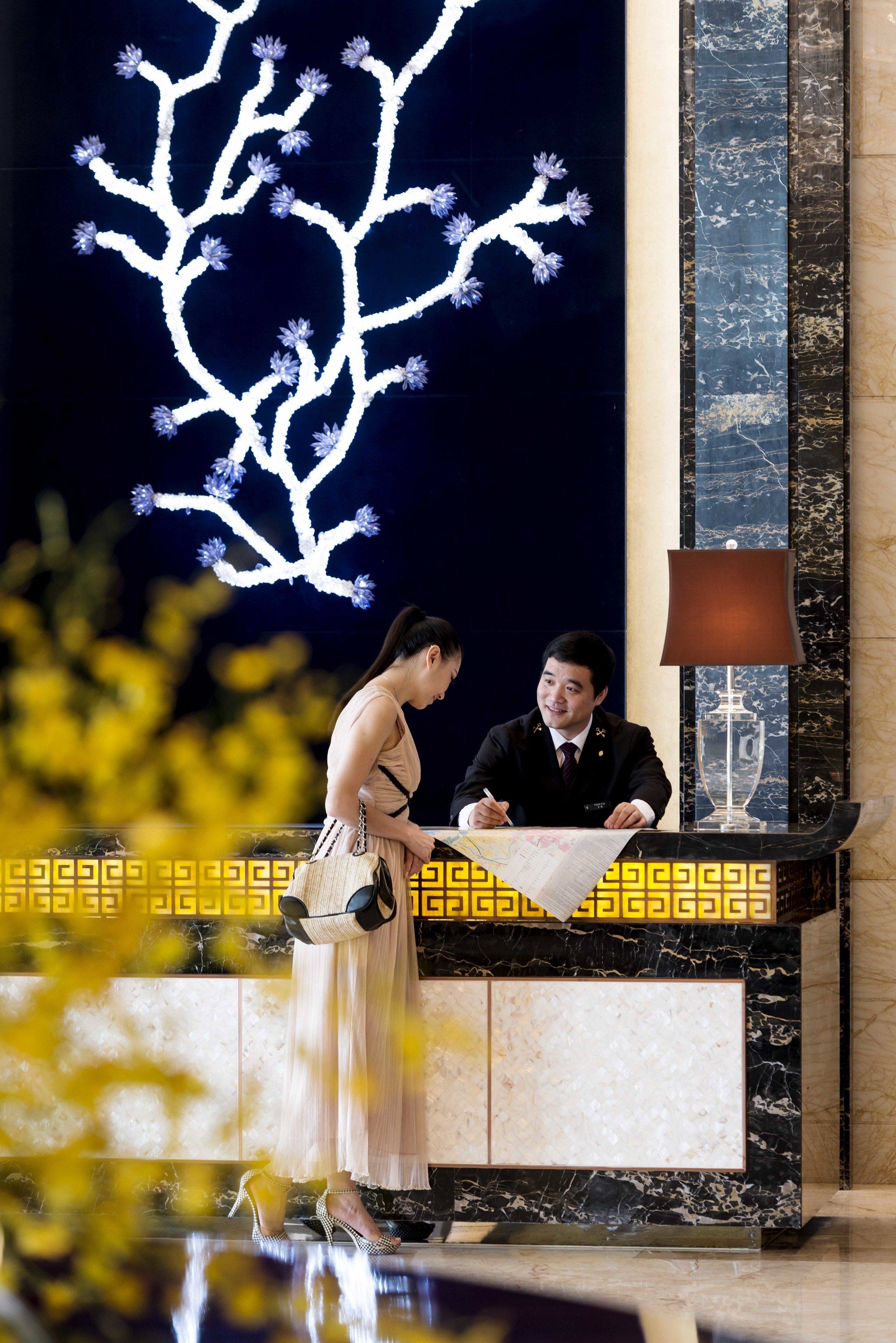 Una reception con un bancone in marmo e un'ampia decorazione a forma di albero illuminato.