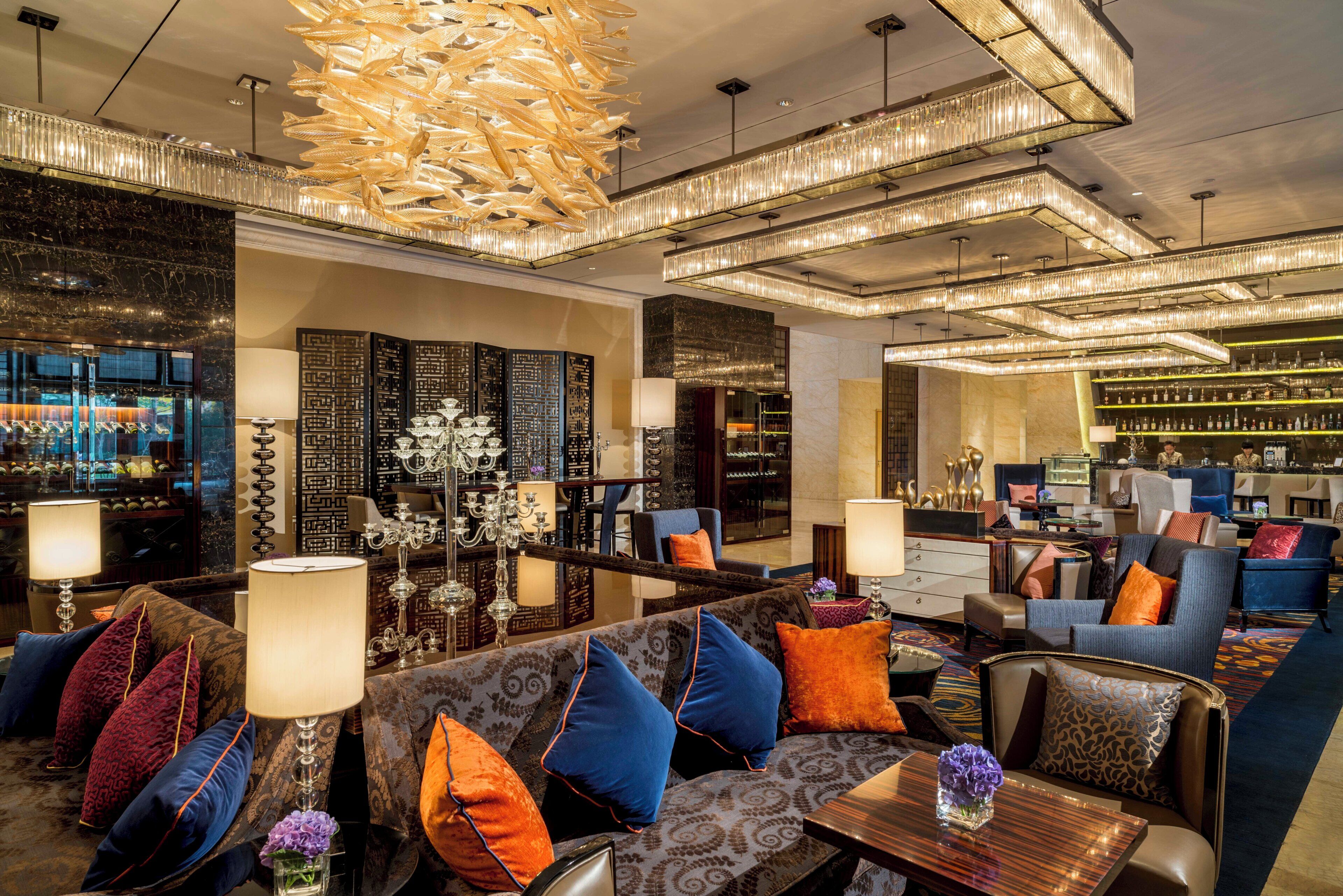 Een ruime lobby met een bar, zitgedeelte en een decoratieve kroonluchter.