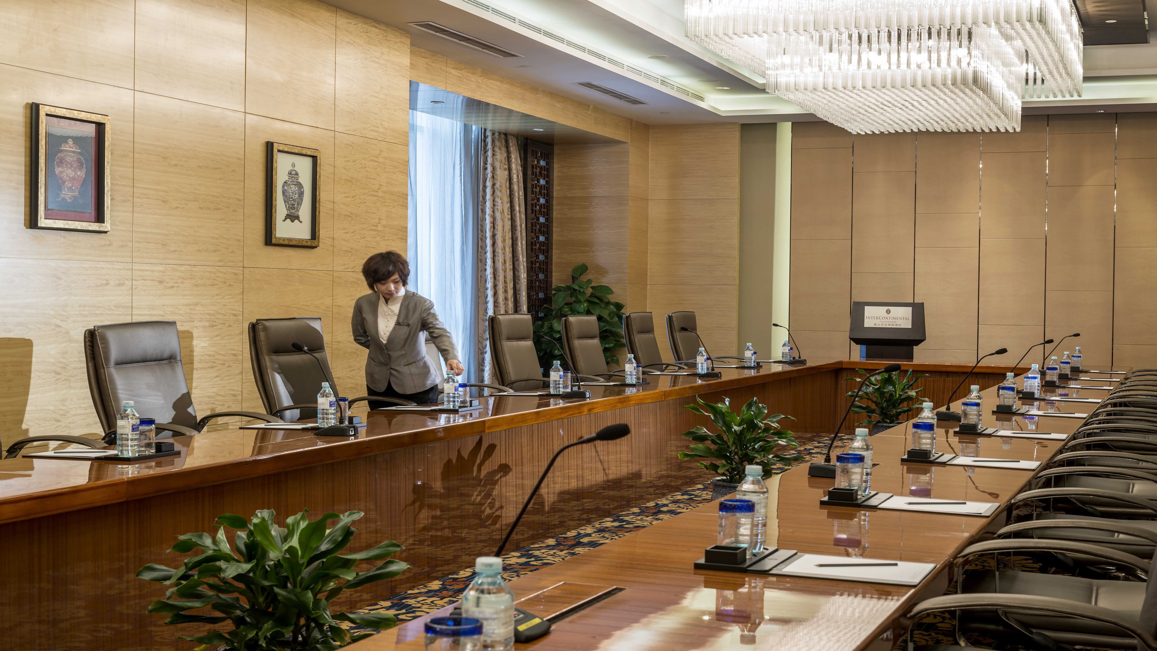 Une salle de conférence avec une longue table, de nombreuses chaises, des bouteilles d’eau et une plaque nominative.