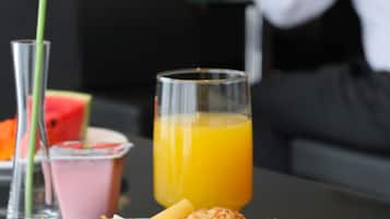 Uma mesa de café da manhã com um prato de comida, um copo de suco de laranja, um copo de leite, uma fatia de melancia e um lírio elegante.
