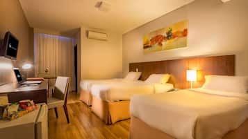 A hotel room with two beds, a desk with a laptop, a TV, and a painting on the wall.