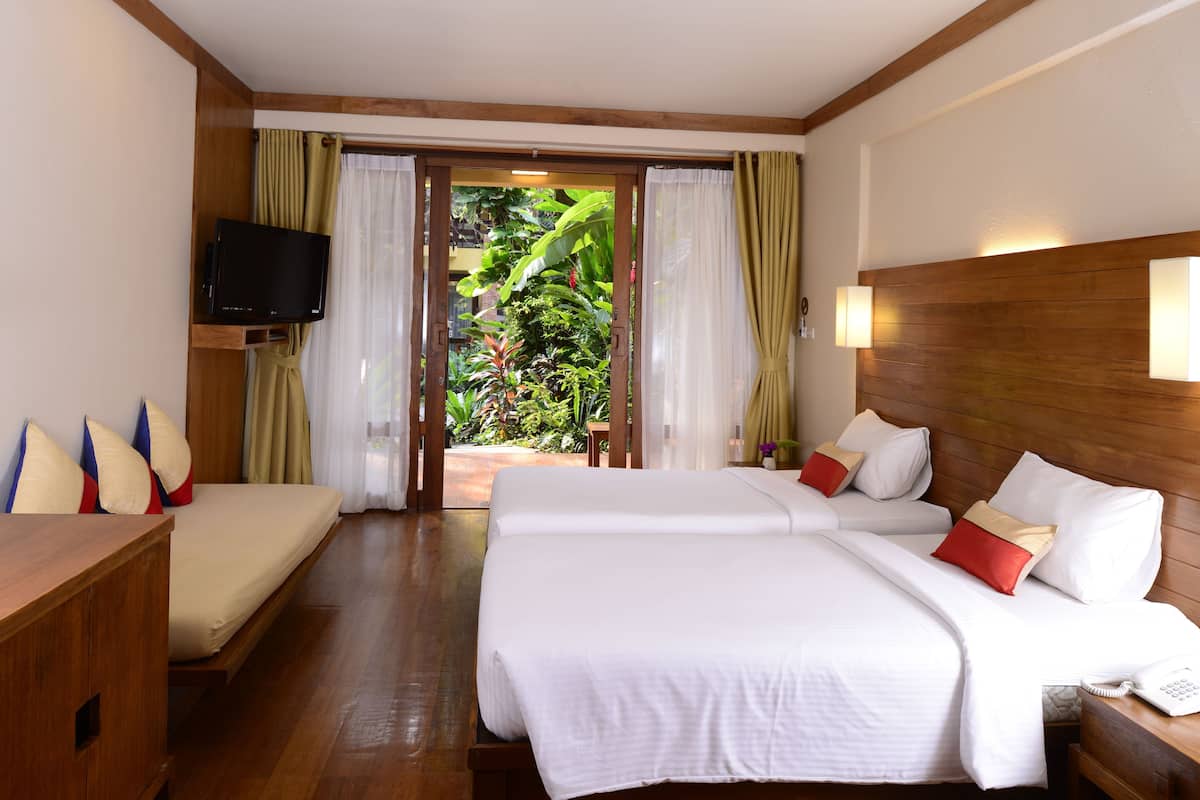 Une chambre d’hôtel avec deux lits, une télévision et une vue sur un jardin luxuriant.