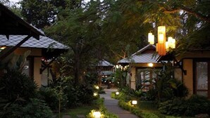 A pathway lined with small, illuminated lanterns leading to traditional-style buildings surrounded by lush greenery. - Baan Talay Dao (Hua Hin)