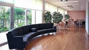 A modern interior with a curved sofa, large windows, and a dining area. - Hirata MAPLE Hotel (Izumo)