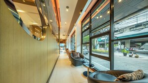 A modern hotel lobby with a long corridor, seating areas, and large windows offering views of the street. - M2 de Bangkok (Bangkok)