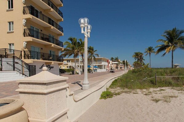 A beachfront hotel with multiple balconies, a sandy walkway, and palm trees. - HOLLYWOOD SUNRISE (Hollywood)
