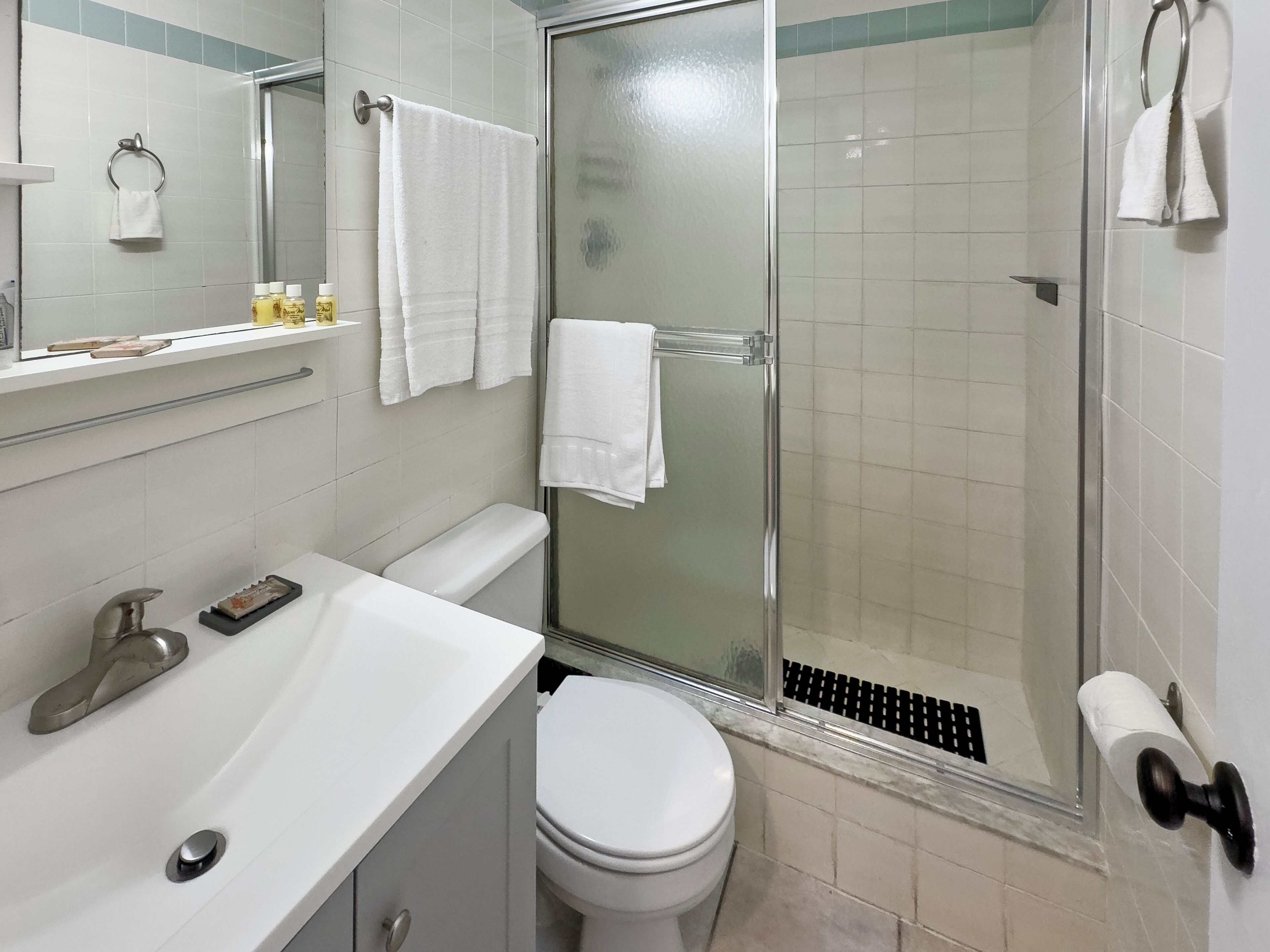 Ein Badezimmer mit weißem Waschbecken, Toilette und Duschkabine aus Glas.