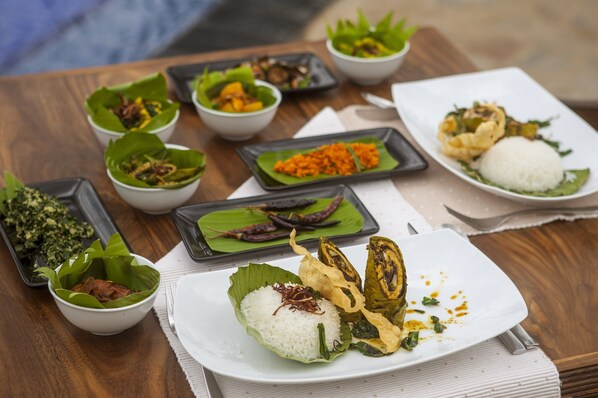 A variety of dishes served on a wooden table, including rice, vegetables, and fried items, with a focus on presentation and variety.